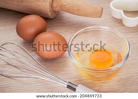 Fresh egg in bowl and metal whisk