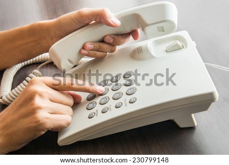 Female hand dialling out on a landline telephone pressing on the keypad