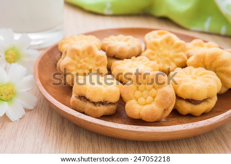 Flower shape biscuits with jam filling on wooden plate