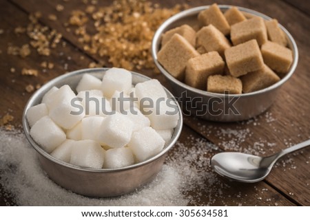 White sugar and brown sugar in bowl on wooden table