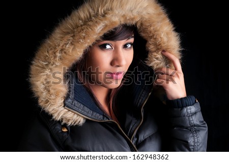 Beautiful young woman wearing a parka with imitation fur lining.