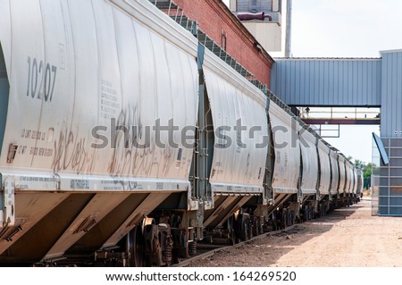 Line of covered hopper railcars being loaded with dry-bulk product at the source mill.