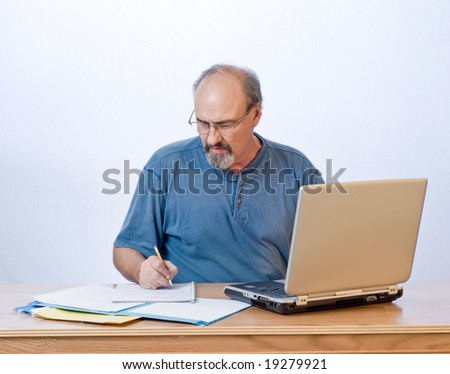 A businessman takes notes from the computer search results.