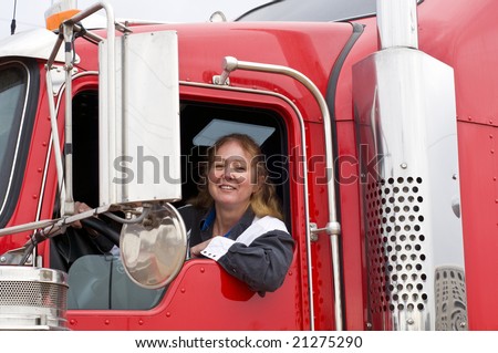 Woman truck driver leaning out the drivers side window. - stock photo