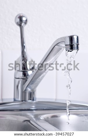 Water dribbling from a leaking faucet on the kitchen sink.