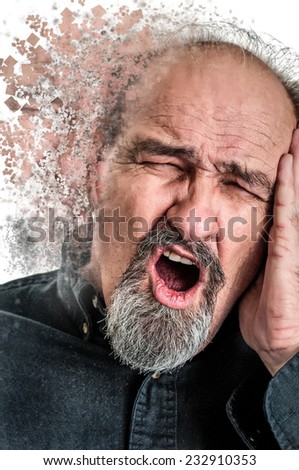 Balding man in his sixties holding his head in pain from a headache as he shouts.
