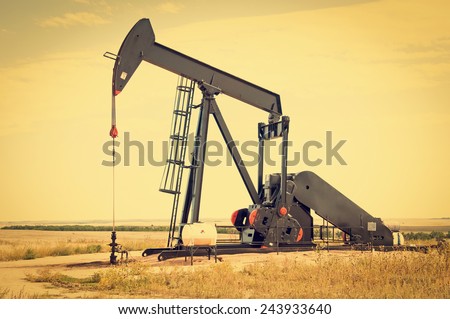 Raised pump jack in south central Colorado, USA, ready to start the down stroke to load the lifting pump with crude oil. Retro instagram look.