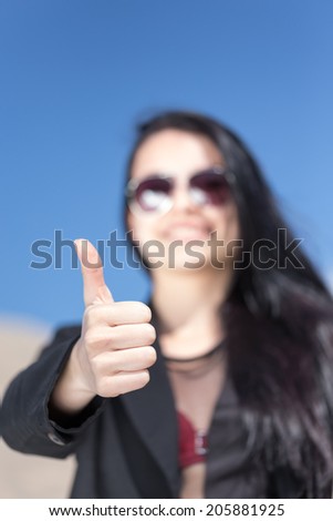 business girl in black dress with sunglasses smiling with hands up