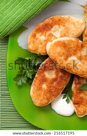 Fried pies on the green dish with sour cream