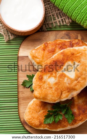 Fried pies on the green dish with sour cream