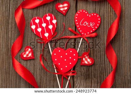 Variety of red hearts with ribbons on vintage wooden background for valentine\'s day holiday