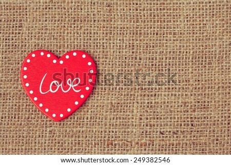 Red valentine's day holiday heart on retro textile background with vintage instagram toning