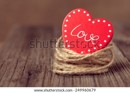 Red valentine\'s day holiday heart with text in nest on wooden background with vintage instagram toning