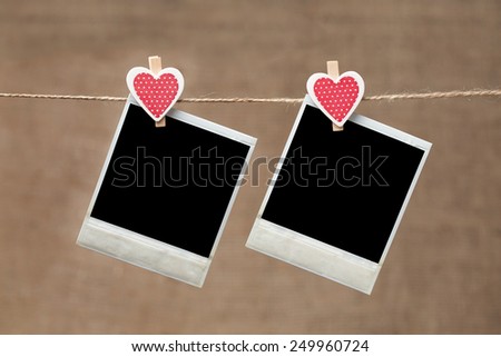 Two polaroid photo frames for valentines day hanging on vintage background
