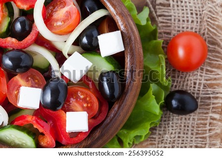 Traditional greece salad with olives, tomato, cucumber and feta on wooden background top view