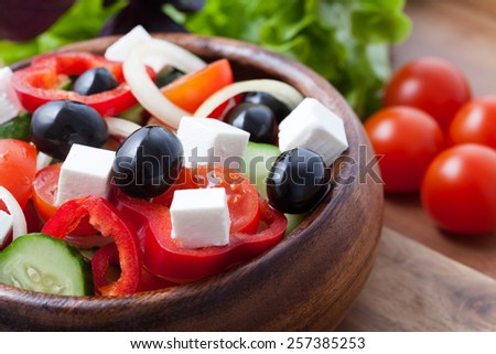 Traditional greece salad with olives, tomato, cucumber and feta in a wooden bowl