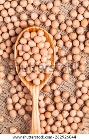 Healthy raw chickpeas nutrition super food in wooden spoon on vintage textile background