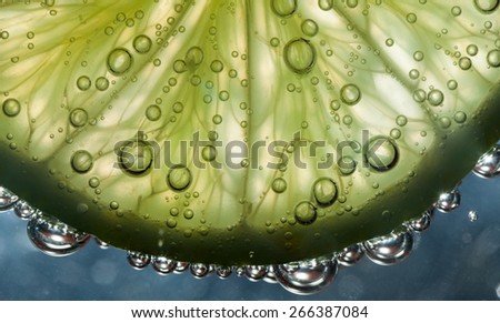 Slice of transparent lime in water with bubbles. Close up shot