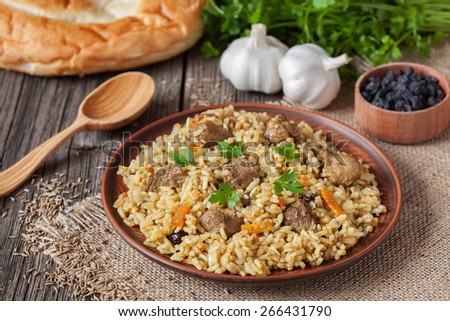 Traditional uzbek meal called pilaf. Rice with meat, carrot and onion in vintage plate on wooden background