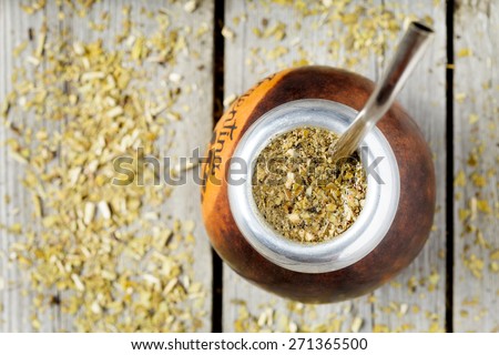 Traditional Argentina yerba mate tea beverage in calabash and bombilla in rustic style on vintage wooden background