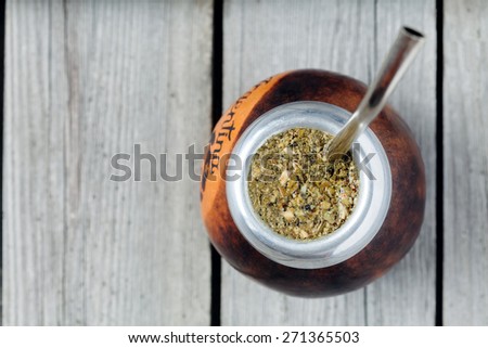 Healthy yerba mate tea in kalabash with bombilla in rustic style on vintage wooden background
