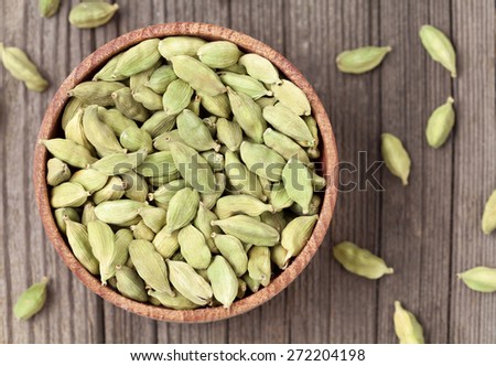 Green cardamom ayurveda plant aroma spice in a wooden bowl on vintage background