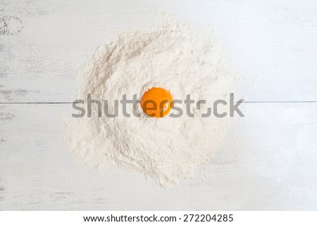 Dough raw ingredients on white table background. Egg yolk and flour