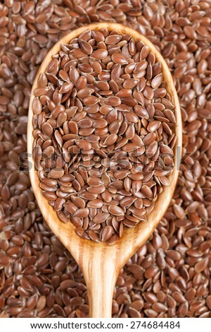 Healthy little brown flax seeds super foods  in wooden spoon. Organic vegetarian super food.