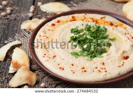 Plate of hummus, healthy lebanese traditional creamy food with chick-peas, tahini and pita flatbread on vintage wooden background