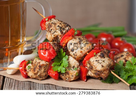 Delicious traditional chicken or turkey kebab skewer barbecue meat with vegetables, green onion and beer on bamboo sticks. Served on kitchen table background. Rustic style, natural light.