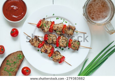 Delicious roasted turkey kebab skewer barbecue meat with vegetables, bread, sauce and beer on white dish. Served on kitchen table background. Rustic style, natural light.
