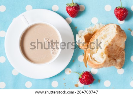 Concept of perfect lunch or breakfast. A cup of coffee latte with a piece of traditional French croissant pasrty and fresh strawberries on provence style background. Rustic style and natural light.