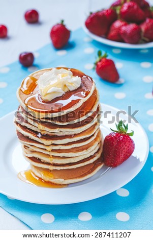 Pancakes traditional American homemade sweet dessert with honey, butter and strawberry on provence style background. Rustic style and natural light