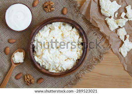 Cottage cheese healthy protein breakfast with sour cream and almond nuts in rustic wooden dish on vintage kitchen table background. Rustic style, natural light.