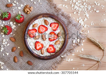Healthy breakfast oatmeal porridge diet nutririon with strawberry and nuts. Organic vegetarian meal. Vintage wooden table background. Rustic style and natural light.