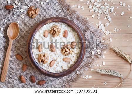 Healthy homemade oatmeal porridge with nuts. Perfect vegetarian diet breakfast concept. Vintage wooden table background. Rustic style and natural light