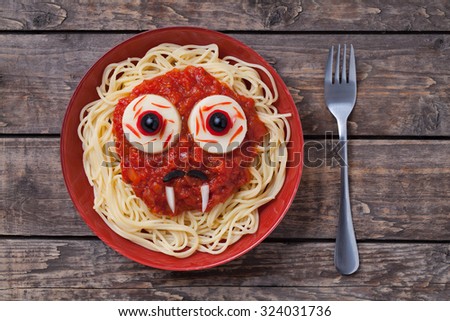 Halloween scary pasta food vampire face with big eyes and moustaches in red dish for celebration party decoration on vintage wooden table background