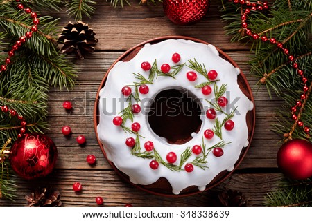 Traditional homemade christmas cake holiday dessert with cranberry in new year tree decorations frame on vintage wooden table background. Rustic style. Top view