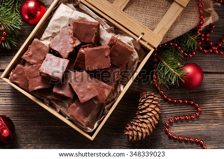 Christmas fudge traditional homemade chocolate sweet dessert food in wooden box on vintage table background. Top view. Delicious unhealthy treat.
