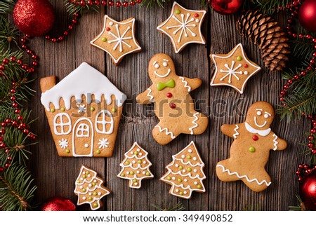 Gingerbread man and woman, house, fir trees and stars cookies composition with christmas decorations on vintage wooden table background. Homemade traditional recipe