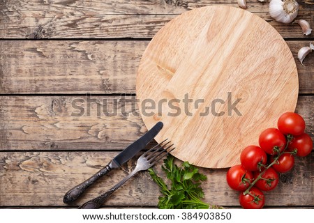 Pizza cutting board template with empty space for advertising design. Round rustic wooden plate with tomatoes on vintage wooden background. Top view rustic style.