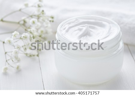 Healthy cosmetic cream with herbal flowers face care hygiene moisture lotion therapy in glass jar with towel on white background