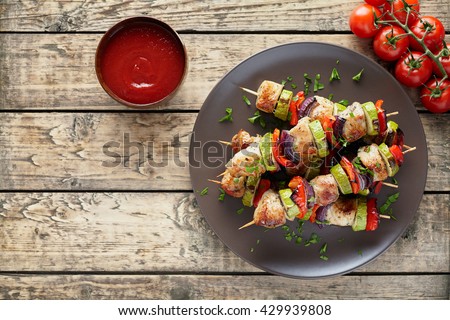 Turkey or chicken meat shish kebab skewers with ketchup sauce, and tomatoes on rustic wooden table background. Traditional barbecue grill shish food