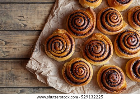 Freshly baked cinnamon buns with spices and cocoa filling on parchment paper. Top view. Sweet Homemade Pastry christmas baking. Close-up. Kanelbule - swedish dessert.