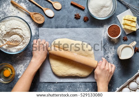 Dough bread, pizza or pie recipe homemade preparation. Female baker hands rolling dough with pin. Food ingridients flat lay on kitchen table. Working with pastry or bakery cooking. Top view