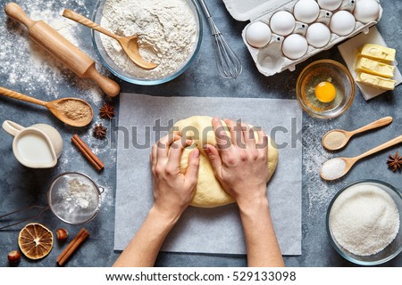 Baker knead dough bread, pizza or pie recipe ingridients with hands, food flat lay on kitchen table background. Working with butter, milk, yeast, flour, eggs, sugar pastry or bakery cooking.