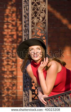 beautiful young woman reaching and looking out of a balcony