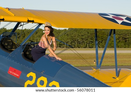 pinup girl standing in a vintage biplane back seat