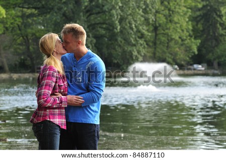 happily married couple kissing out in the park
