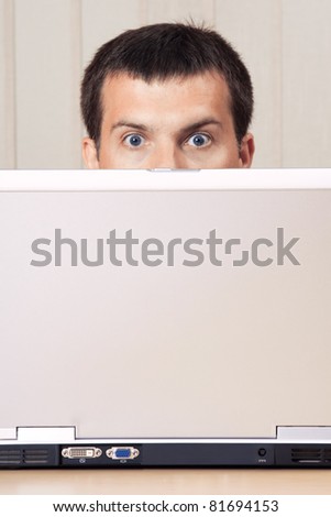 A man hiding behind a laptop display